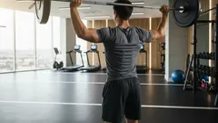 Muž posiluje s činkou v moderní posilovně, cvičení se závažím, fitness trénink